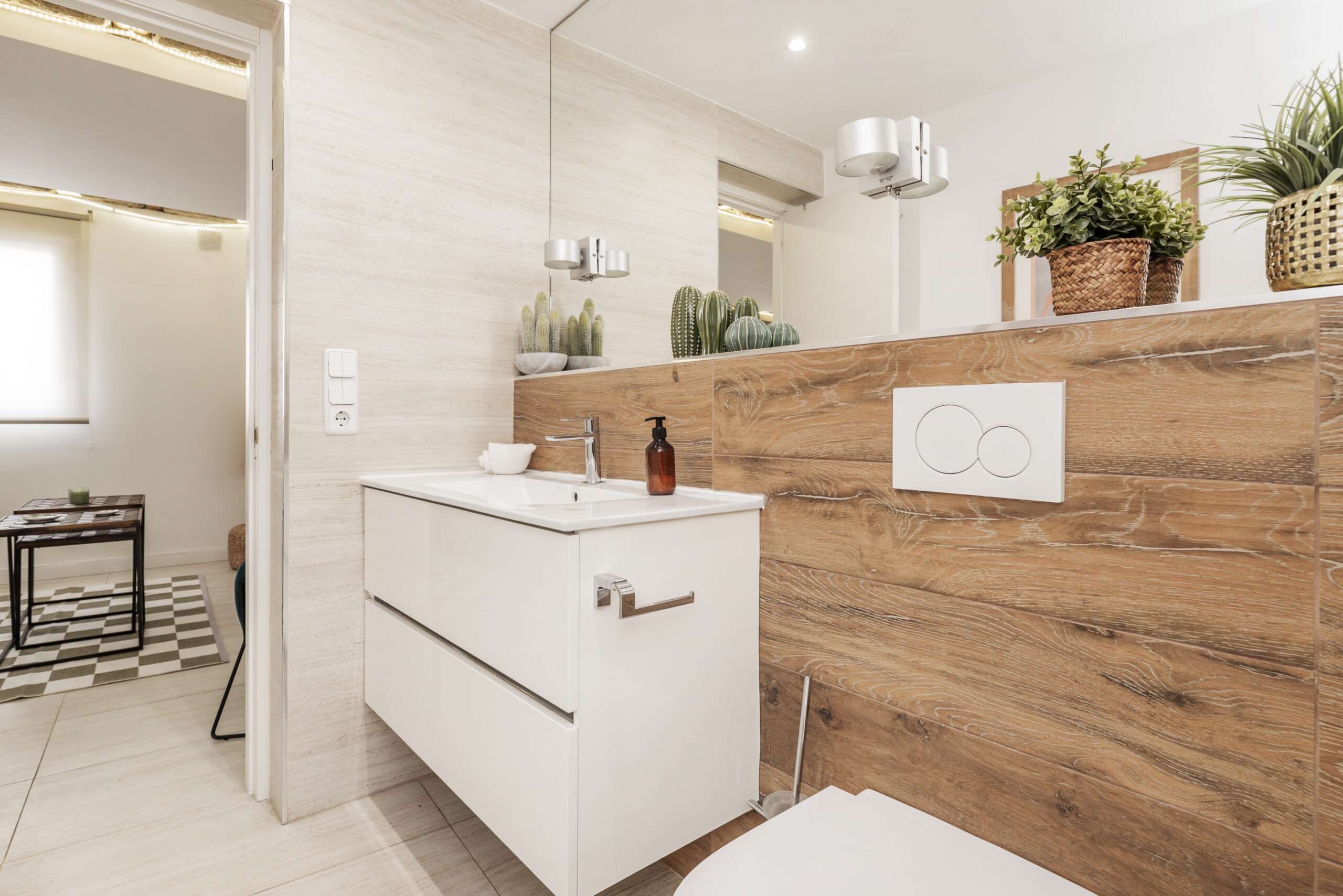 A bathroom with wood-like stoneware tiles, white wooden furniture, endless mirror integrated into the wall, white porcelain sink and stoneware floor